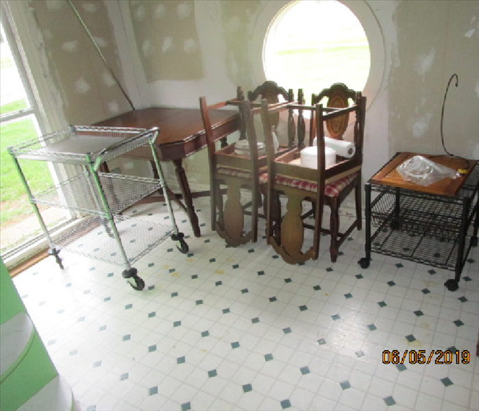 Picture of the eat in area after cleaning, with the wallpaper removed and the table & chairs stacked to one side