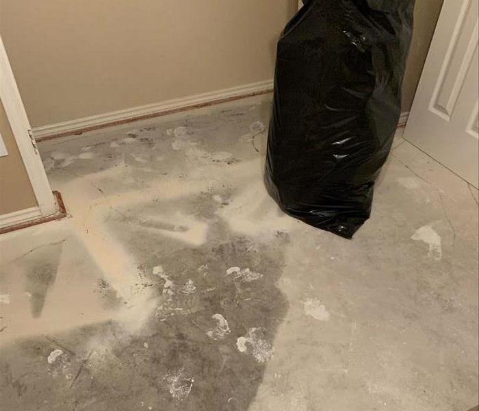 Photo of carpet rolled back, pad removed and water pattern running from under the wall is apparent