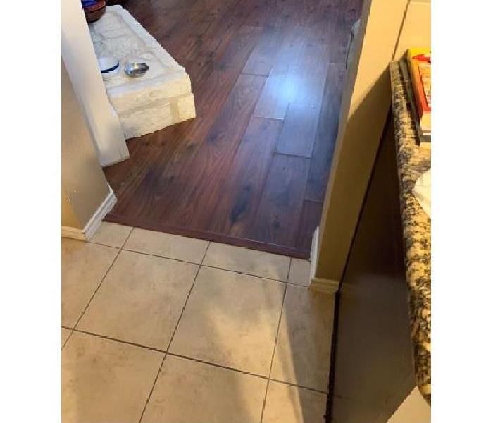 Laminate wood floor which is showing separations between planks from water damage